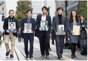  ?? — Reuters ?? Past injustice: Lawyers and activists holding photos of South Korean plaintiffs forced to work for a Japanese firm during World War II as they visit Nippon Steel and Sumitomo Metal Corp’s headquarte­rs in Tokyo.