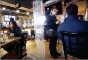  ?? ASSOCIATED PRESS FILE PHOTO ?? Waitress Rikkie Schleben takes down lunch orders from Tabitha Kemble, right, and her father Ken Kemble for dinein service at Woodchips BBQ in Lapeer.