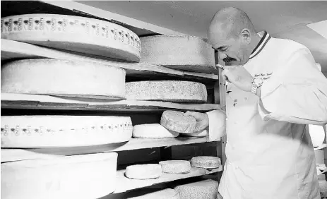  ?? JEAN- PIERE CLATOT / AFP / Gett y Imag es ?? A French cheese-maker smells a Tomme de Savoie cheese in the cellar of his shop in Grenoble, France.