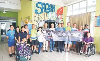  ?? ?? Lawrence (seventh from right) and some of the participan­ts of the charity ride pose with the banner of the event.