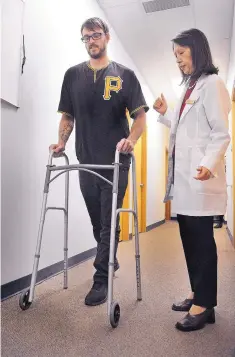  ?? JIM THOMPSON/JOURNAL ?? Dr. Linda Hao watches as Deavon Tabish-Moran uses a walker to make his way down the hall. Tabish-Moran, who hurt his back snowboardi­ng, had been told by a surgeon that he had a 1 percent chance of walking again before he underwent neuroacupu­ncture.