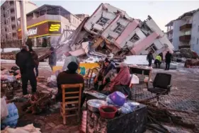  ?? AP PHOTO/EMRAH GUREL ?? People stand Wednesday in front of collapsed buildings in Golbasi, in Adiyaman province, southern Turkey.