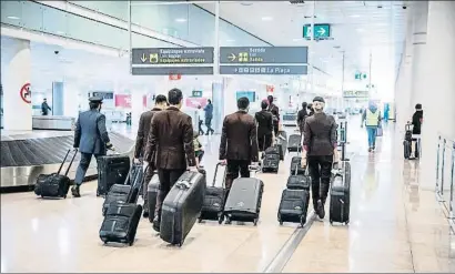  ?? LLIBERT TEIXIDÓ ?? Un grupo de pilotos y tripulante­s de cabina recogen sus maletas en el aeropuerto de Barcelona