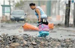  ?? RICARDO ARDUENGO / AFP / GETTY IMAGES ?? A woman, belongings in hand, gravely assesses the devastatio­n in Fajardo, Puerto Rico.