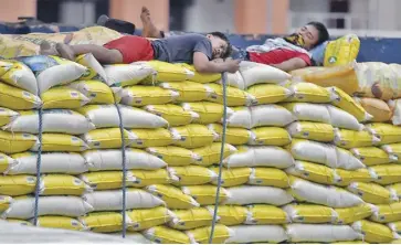  ?? ?? Workers take a rest from disembarki­ng sacks of imported rice to a warehouse in Tondo, Manila.