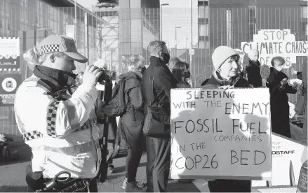  ?? ANDY BUCHANAN/GETTY-AFP ?? An officer records activists protesting on the sidelines of the COP26 summit Thursday in Scotland.