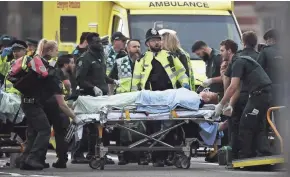  ?? GETTY IMAGES ?? A member of the public is treated by emergency services Wednesday near Westminste­r Bridge and the Houses of Parliament in London.