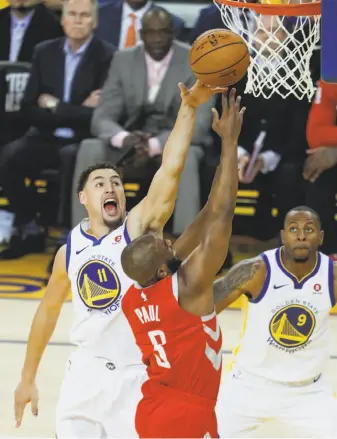  ?? Carlos Avila Gonzalez / The Chronicle ?? Warriors guard Klay Thompson, with teammate Andre Iguodala watching, blocks a shot by Rockets guard Chris Paul during the first quarter of Game 3 of the Western Conference finals.