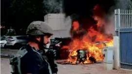  ?? JACK GUEZ/AFP VIA GETTY IMAGES ?? An Israeli security forces member stood close to a car hit by rocket fired from Gaza, in the southern Israeli city of Sderot.