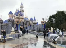  ?? Associated Press ?? Maskless visitors take photos before the COVID-19 shutdown at Disneyland in Anaheim, Calif., in March 2020.