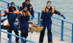  ??  ?? SOCHI: Russian rescuers carry a stretcher with a recovered body on a pier after a Russian military plane crashed in the Black Sea yesterday. — AFP