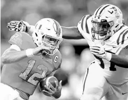  ?? RONALD MARTINEZ/GETTY IMAGES ?? UM QB Malik Rosier (12) tries to elude the tackle of LSU’s Glen Logan during Sunday’s season-opening AdvoCare Classic at AT&amp;T Stadium in Arlington, Texas.