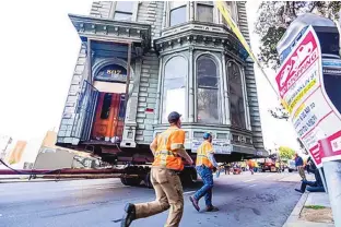  ?? NOAH BERGER/ ASSOCIATED PRESS ?? Workers in San Francisco assist the slow transport of a Victorian home from 1882 to its new location six blocks away, making room for a condominiu­m developmen­t.