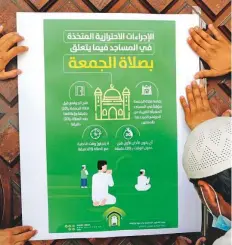  ?? AP ?? Workers place a poster that explains the precaution­ary measures and instructio­ns to be followed inside mosques for Friday prayers at Al Mirabi Mosque in Jeddah yesterday.