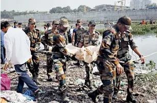  ?? NANDAN DAVE ?? BODY COUNT
Security personnel carry the body of a victim recovered from the Machchhu river