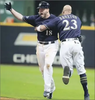  ?? Tannen Maury EPA/Shuttersto­ck ?? MIKE MOUSTAKAS is hugged by Keon Broxton after his walk-off single in the 10th inning against the Rockies, who had rallied for two runs in the ninth inning to tie it.