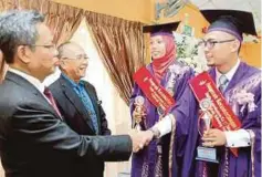  ??  ?? MOHD Razali (kiri) bersama Zulkifli mengucapka­n tahniah kepada graduan terbaik, Muhammad Hazwan dan Siti Adayu.