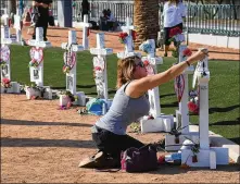  ?? ETHAN MILLER GETTY IMAGES ?? Ashley Schuck of Nevada places a medal she got for running in Saturday’s Vegas Strong 5Kona cross for shooting victim Neysa Tonks on Monday in Las Vegas.