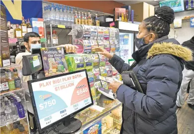  ?? PAUL W. GILLESPIE/CAPITAL GAZETTE PHOTOS ?? Main Street Mini Market owner Amit Nibber, left, sells Powerball and Mega Millions tickets to Denise Carrington on Thursday. The combined jackpot this weekend is now over $1 billion for upcoming drawings tonight and Saturday.