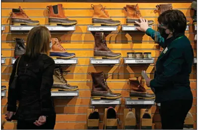  ??  ?? An employee helps a customer shop for Bean Boots last month at the L.L. Bean flagship retail store in Freeport, Maine. Retail sales surged a seasonally adjusted 9.8% in March, the Commerce Department said Thursday.