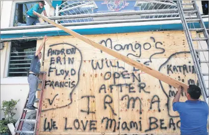  ?? AP PHOTO ?? Workers shutter Mango’s Tropical Cafe in Miami Beach, Fla., Thursday.