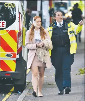  ?? AP/PA/DOMINIC LIPINSKI ?? An injured woman is assisted by a police officer Friday close to Parsons Green station in west London after an explosion on a packed London Undergroun­d train.
