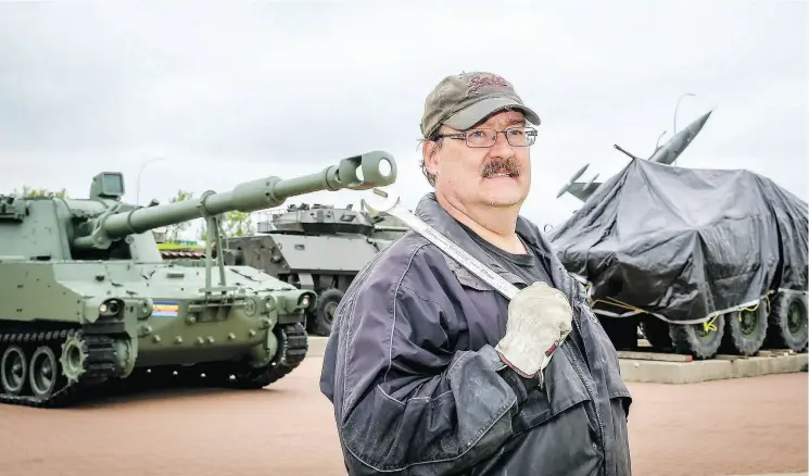  ?? AL CHAREST / POSTMEDIA NEWS ?? Volunteer Brian McGregor prepares to work on the Calgary Military Museum’s newest addition, a light armoured vehicle called the LAV III, covered in a tarp at right.