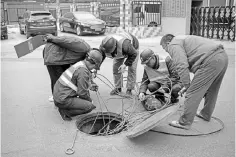  ??  ?? Workers pull cables out of a gutter on a street in Beijing on March 23. China urged the United States on Friday to“pull back from the brink”as President DonaldTrum­p’s plans for tariffs on up to US$60 billion in Chinese goods brought the world’s two...