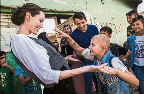  ??  ?? A touching
meeting: Jolie interactin­g with Falak, eight, during a visit to West Mosul. Falak has a gene disorder and PTSD – she spoke to Jolie about seeing a man killed in front of her during the IS group occupation of the city. Less than a year after...