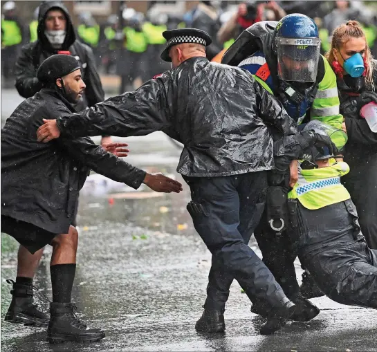  ??  ?? OFFICER DOWN: The badly injured rider who fell from her horse is rescued by colleagues, who drag her away from the violence that erupted during the Black Lives Matter anti-racism protest in central London yesterday