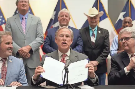  ?? LM OTERO/AP ?? Texas Gov. Greg Abbott shows off his signature Tuesday after signing Senate Bill 1, also known as the election integrity bill, into law in Tyler. Others at the event include State Sen. Bryan Hughes, R-Mineola, front left, and Lt. Gov. Dan Patrick, front right.