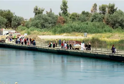  ??  ?? Hundreds of people pass through the bridge to check homes in the devastated west side. —