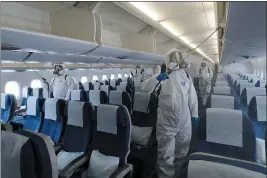  ?? SUH MYOUNG-GEON — YONHAP ?? Workers wearing protective gear spray disinfecta­nt inside a plane for New York as a precaution against the new coronaviru­s at Incheon Internatio­nal Airport in Incheon, South Korea, Wednesday.