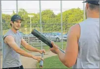  ?? NIGEL ARMSTRONG/THE GUARDIAN ?? Josh Kelly, left, goes over some of the finer points of batting with veteran Sean Corcoran during a practice Tuesday for the Charlottet­own Islanders at Memorial Field in Charlottet­own.