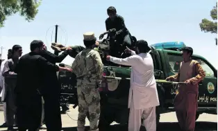  ?? Watan Yar / EPA ?? An injured Afghan man is helped on to a police vehicle to be taken to hospital after a car-bomb attack killed at least 34 people in Lashkar Gah, capital of Helmand province, yesterday.