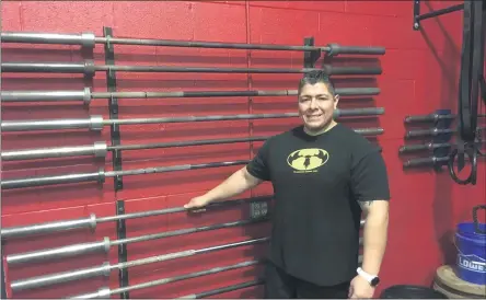  ?? BILL DEBUS — THE NEWS-HERALD ?? Michael Cedeno poses beside an assortment of weightlift­ing bars inside of his new business, Dukes Barbell Club in Perry Village. Cedeno, who is a certified personal trainer and nutrition coach, opened the gym on Dec. 29.