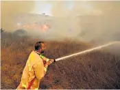  ??  ?? Palestinia­n protesters in the Gaza Strip prepare to launch a kite loaded with an incendiary, left. A firefighte­r in Nir Am attempts to tackle a blaze, above