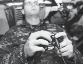 ?? Steven Hoskins, U.S. Navy ?? Lt. j.g. William Gregory uses an Xbox game controller to maneuver the photonics mast aboard the USS Colorado. The submarine is the first to use the new controller­s.
