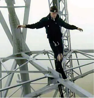  ??  ?? Crazy: The young men filmed themselves walking along narrow girders high up the tower, right, which was shrouded in fog