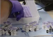  ??  ?? Vials of the Pfizer- BioNTech COVID- 19 vaccine are removed from cold storage on Tuesday at UC Davis Health.