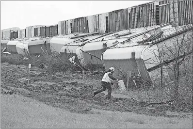  ?? [RALPH BARRERA/AUSTIN AMERICAN-STATESMAN] ?? A worker walks by a train that derailed early Monday in Thrall, Texas. Severe storms pushed at least three tornadoes through parts of San Antonio overnight, ripping the roofs off homes and damaging dozens of other houses and apartments.