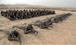  ??  ?? A group of Afghan National Army soldiers watch others participat­e in a live fire exercise at the Afghan Military Academy, in Kabul.