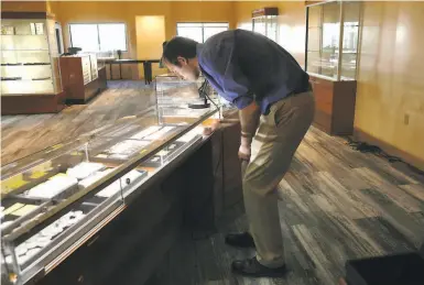  ?? Photos by Liz Hafalia / The Chronicle ?? Sales manager James Andrews views rare coins in the display case at Witter Coins that has just opened in what once was the old Internatio­nal House of Pancakes on Lombard Street in S.F.’s Marina district.