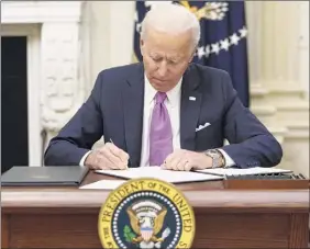  ?? Mandel Ngan / Getty Images ?? President Joe Biden signs executive orders Jan. 21 in the State Dining Room of the White House in Washington, D.C. Experts predict there will be another Covid-specific federal relief package in February.