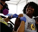  ??  ?? Vyadra Moore smiles at a firefighte­r after he administer­ed her first dose of the Moderna vaccine Friday at the Alamodome.