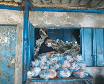  ?? (Mohammed Salem/Reuters) ?? A PALESTINIA­N worker prepares bags of food supplies at an aid distributi­on center run by UNRWA, at Beach refugee camp in Gaza City in April.