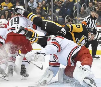  ?? Peter Diana/Post-Gazette ?? Garrett Wilson flips over Hurricanes goaltender Curtis McElhinney in the first period Tuesday night at PPG Paints Arena.