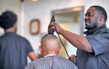  ??  ?? Davon Ivey cuts Master Chief Kevin Harris's hair at Randolph's Barber Shop in Gainesvill­e.