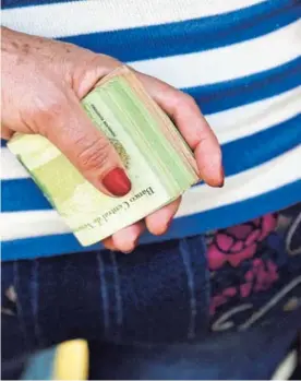 ?? AP ?? Una mujer sostenía un rollo de billetes para pagar un pasaje de bus en Caracas. Se necesita mucho efectivo para las transaccio­nes.