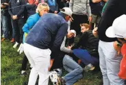  ?? Franck Fife / AFP / Getty Images ?? Brooks Koepka (left) checks on the condition of a fan injured by his errant tee shot.